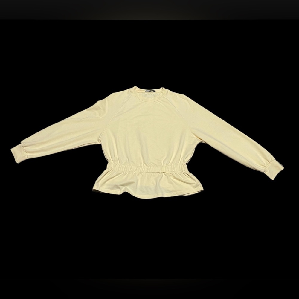 Yellow long sleeve top. Ruffled at the bottom.